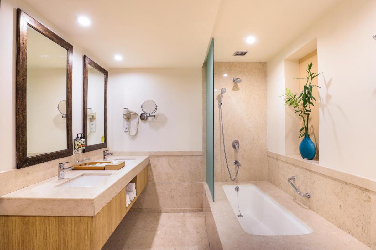 a bathroom with a tub and a sink and a shower at Lemon Tree Premier, Ulsoor Lake, Bengaluru in Bengaluru