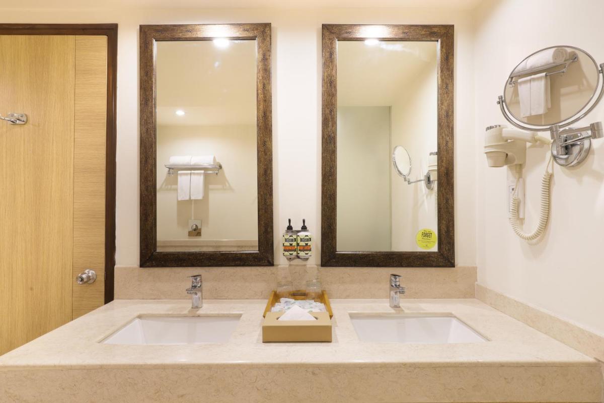 a bathroom with two sinks and two mirrors at Lemon Tree Premier, Ulsoor Lake, Bengaluru in Bengaluru