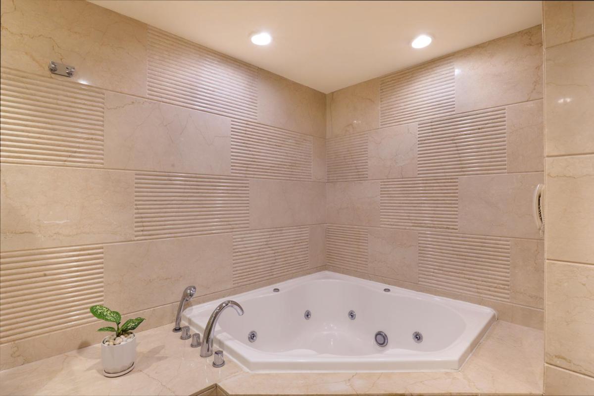a bathroom with a tub and a plant in it at Lemon Tree Premier, Ulsoor Lake, Bengaluru in Bengaluru