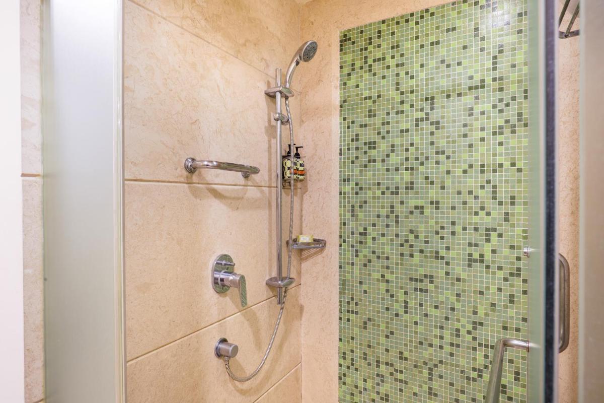 a shower in a bathroom with a glass door at Lemon Tree Premier, Ulsoor Lake, Bengaluru in Bengaluru