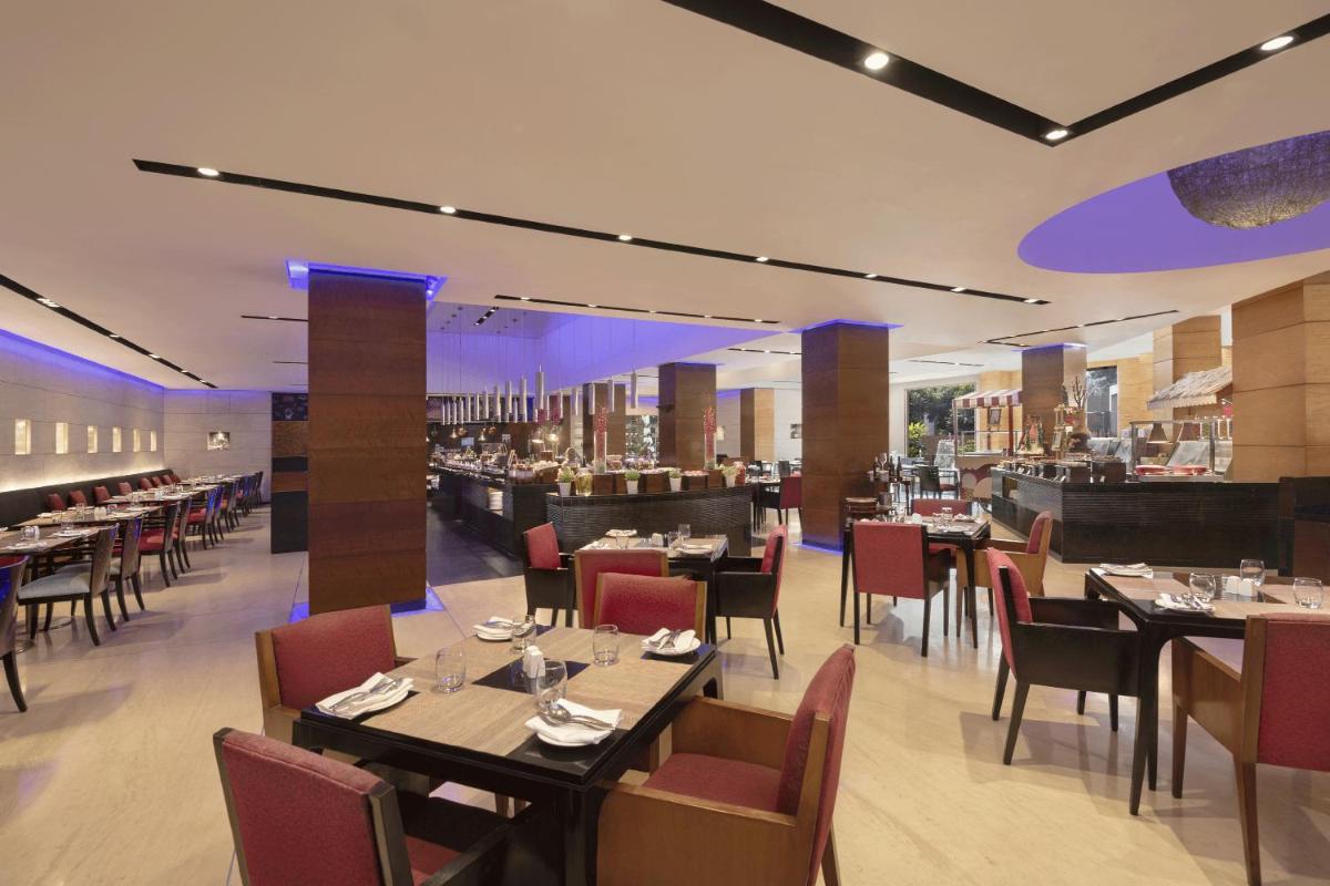 a restaurant with tables and chairs and a bar at Radisson Blu Plaza Delhi Airport in New Delhi a restaurant with tables and chairs and a bar at Radisson Blu Plaza Delhi Airport in New Delhi