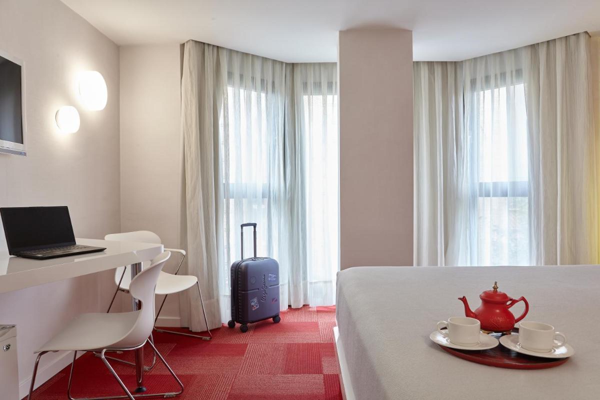 Una habitación de hotel con una cama y un escritorio con una computadora portátil. en Hotel Maciá Granada Five Senses Rooms & Suites, en Granada