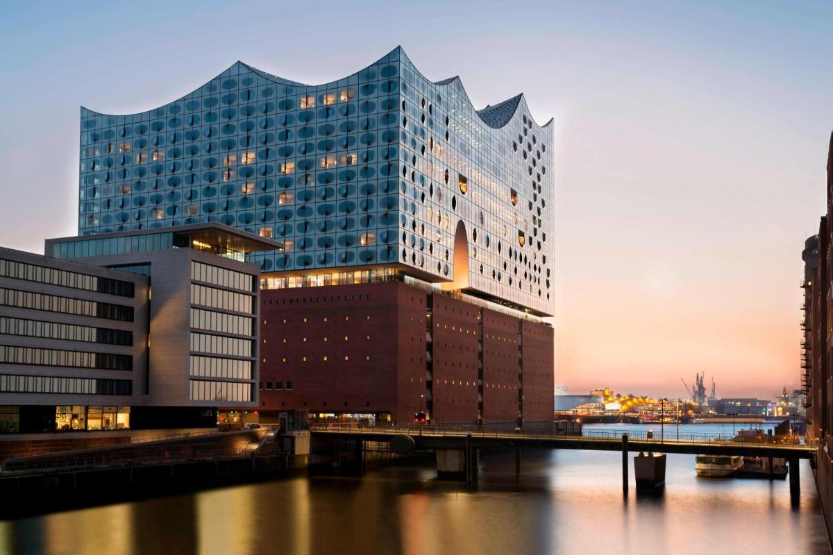 ein großes Gebäude mit einer Brücke vor einem Fluss in der Unterkunft The Westin Hamburg Elbphilharmonie in Hamburg ein großes Gebäude mit einer Brücke vor einem Fluss in der Unterkunft The Westin Hamburg Elbphilharmonie in Hamburg