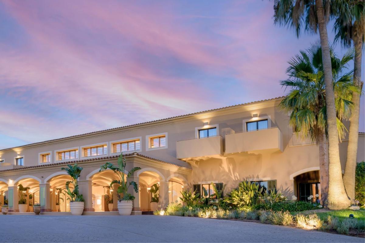 Un gran edificio blanco con palmeras delante. en Hacienda Son Antem Golf Resort, Autograph Collection, en Llucmajor