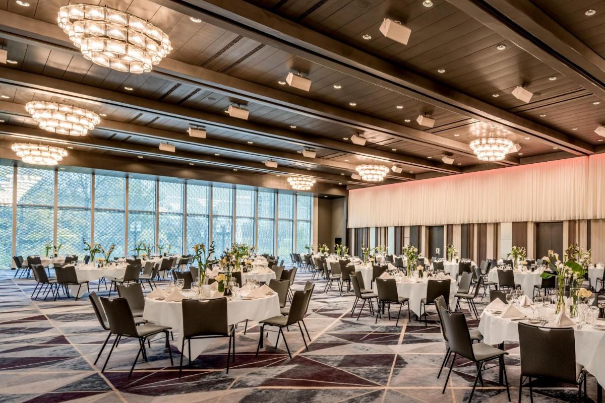 einen Bankettsaal mit weißen Tischen und Stühlen sowie großen Fenstern in der Unterkunft Frankfurt Marriott Hotel in Frankfurt am Main einen Bankettsaal mit weißen Tischen und Stühlen sowie großen Fenstern in der Unterkunft Frankfurt Marriott Hotel in Frankfurt am Main