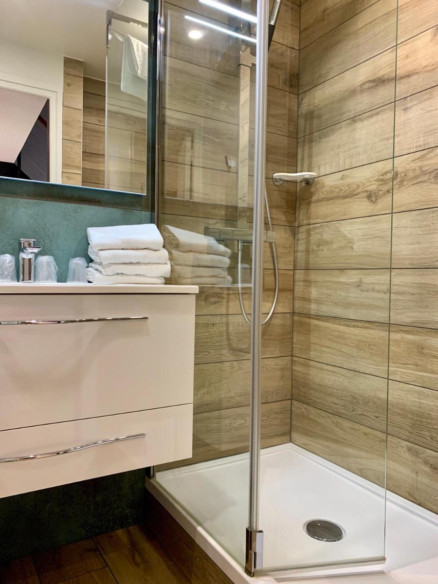 une salle de bain avec douche et porte en verre dans l'établissement Logis Hôtel Restaurant Le Fruitier, à Villedieu-les-Poêles