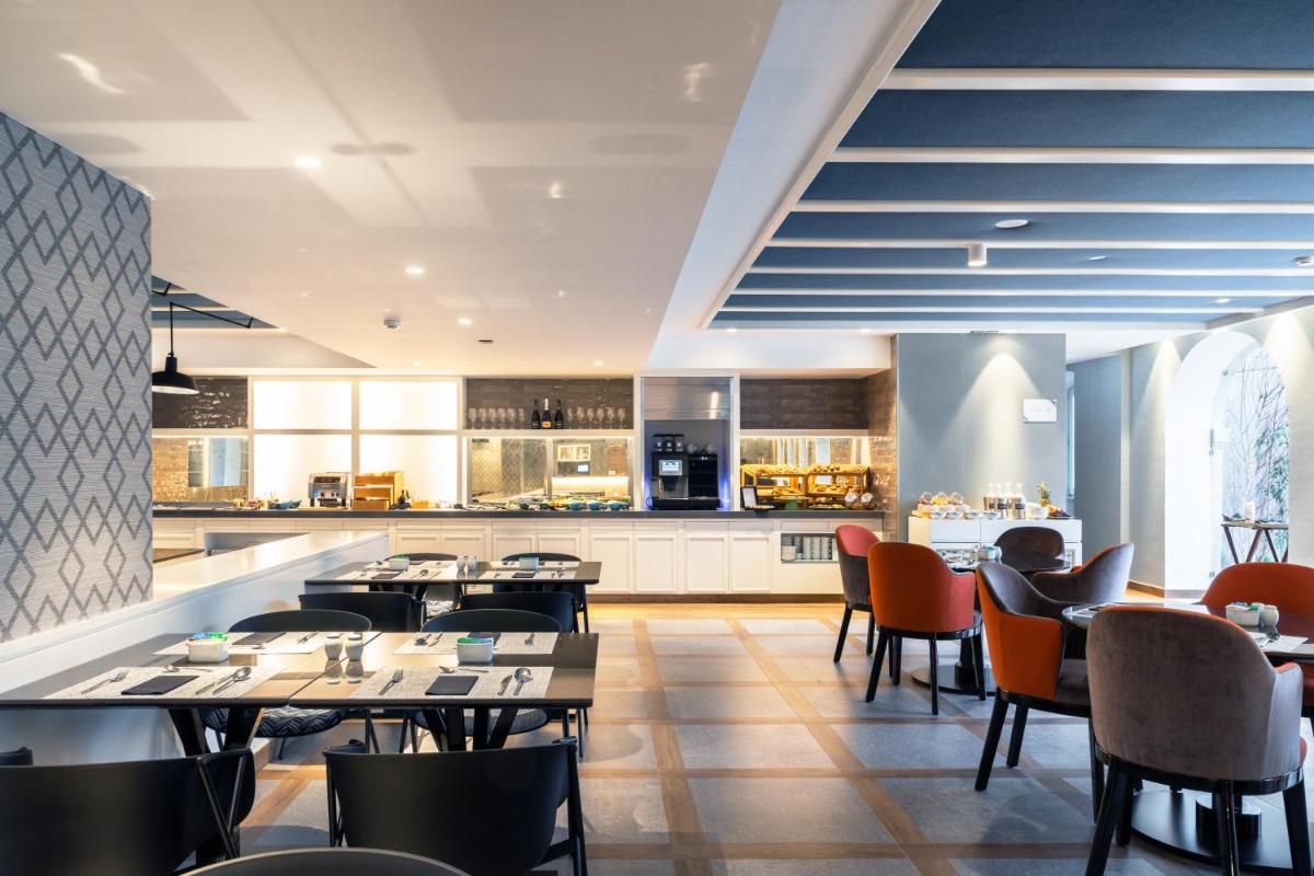 um restaurante com mesas, cadeiras e uma cozinha em Catalonia Porto no Porto