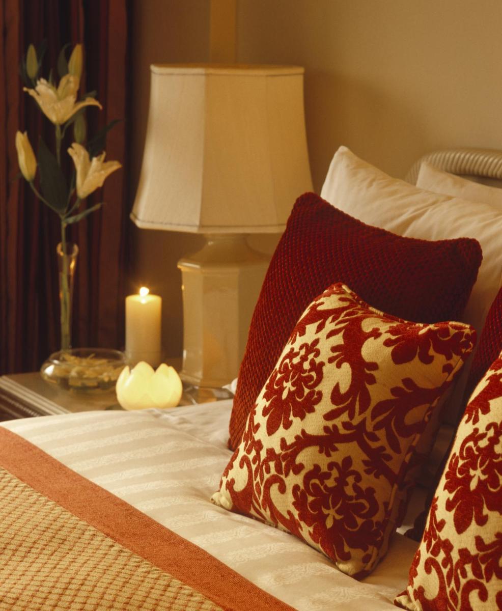 a bed with pillows and a candle on a table at Taj Bengal in Kolkata