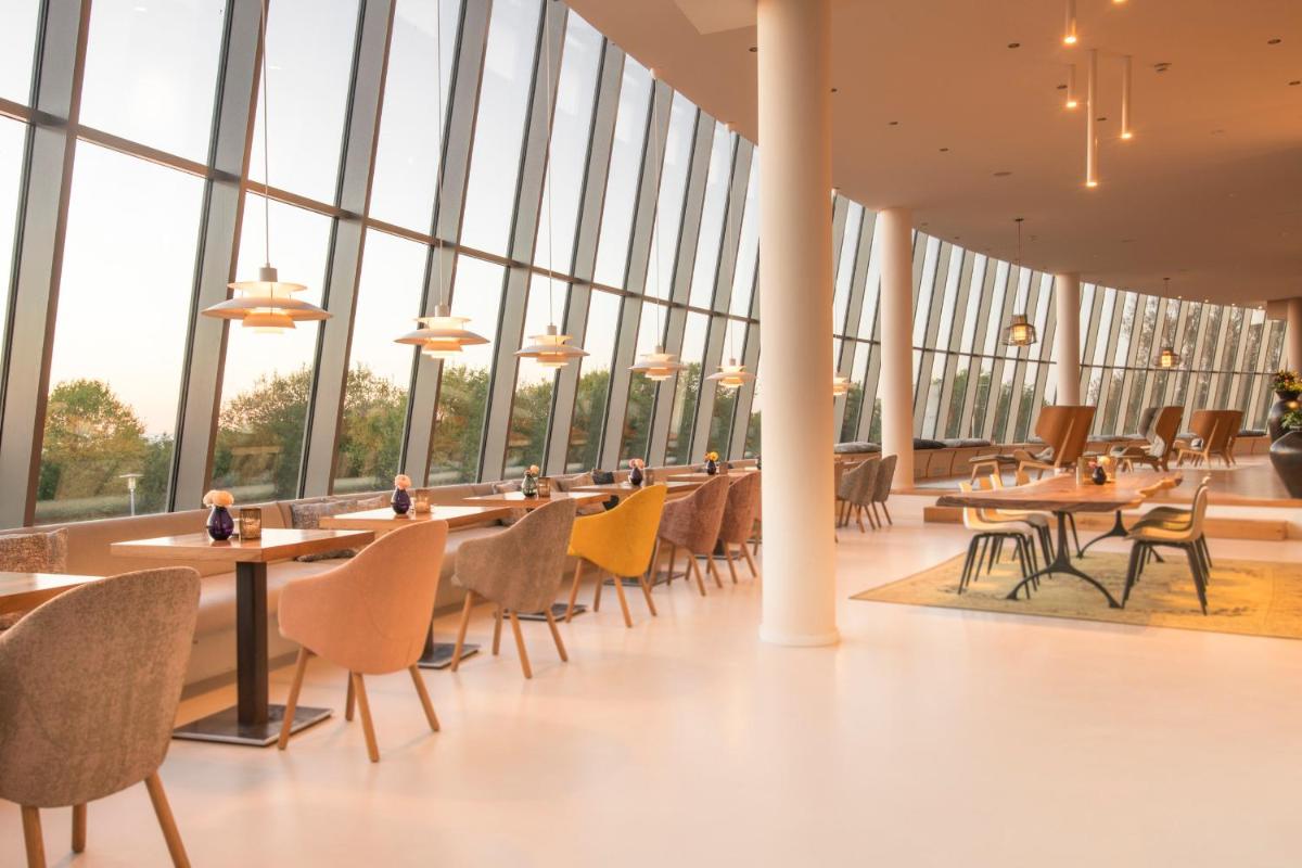 ein Esszimmer mit Tischen, Stühlen und Fenstern in der Unterkunft THE GRAND Ahrenshoop in Ahrenshoop