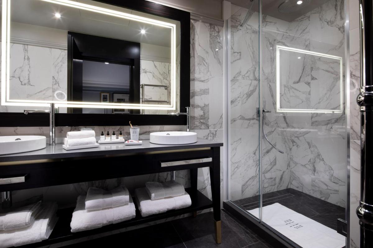 une salle de bain avec deux lavabos et un grand miroir dans l'établissement Le Damantin Hôtel & Spa, à Paris