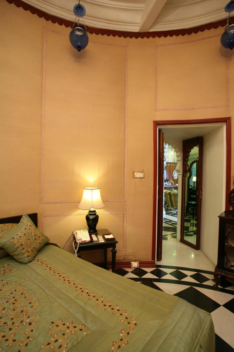 a bedroom with a bed and a table with a lamp at Shiv Niwas Palace by HRH Group of Hotels in Udaipur