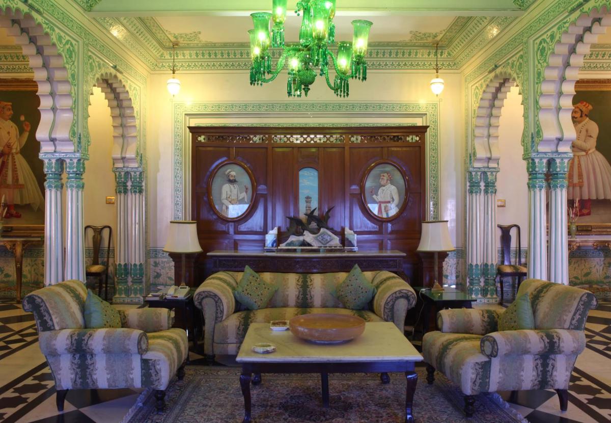 a living room with chairs and a table and a chandelier at Shiv Niwas Palace by HRH Group of Hotels in Udaipur