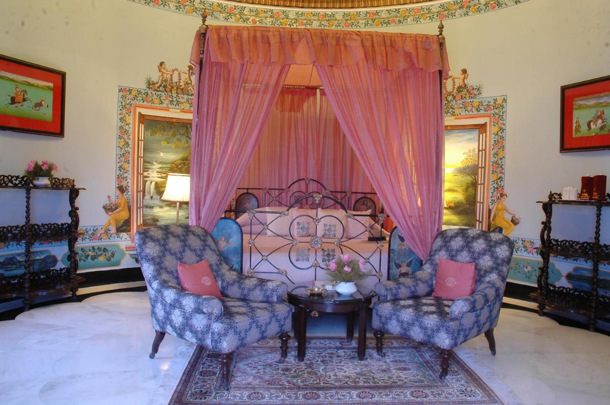 a living room with two chairs and a bed at Shiv Niwas Palace by HRH Group of Hotels in Udaipur