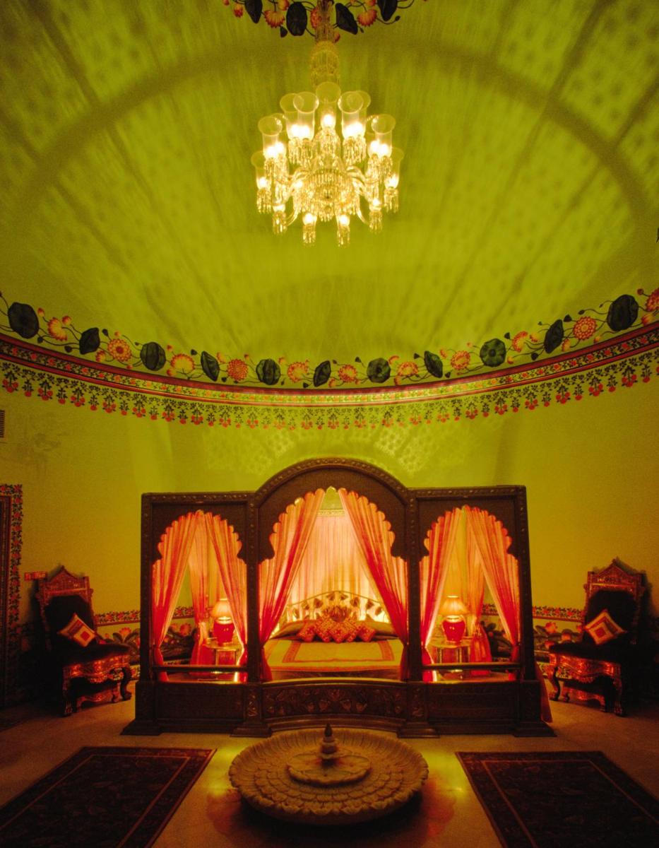 a bedroom with a bed with a chandelier at Shiv Niwas Palace by HRH Group of Hotels in Udaipur