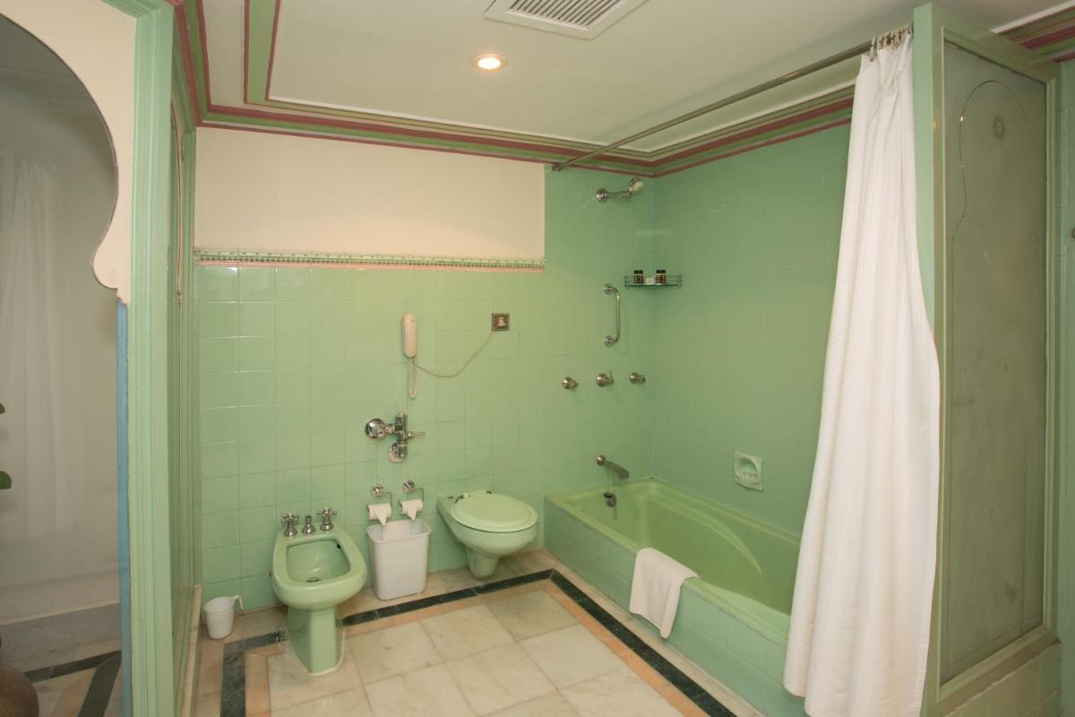 a green bathroom with a toilet and a tub and a sink at Shiv Niwas Palace by HRH Group of Hotels in Udaipur
