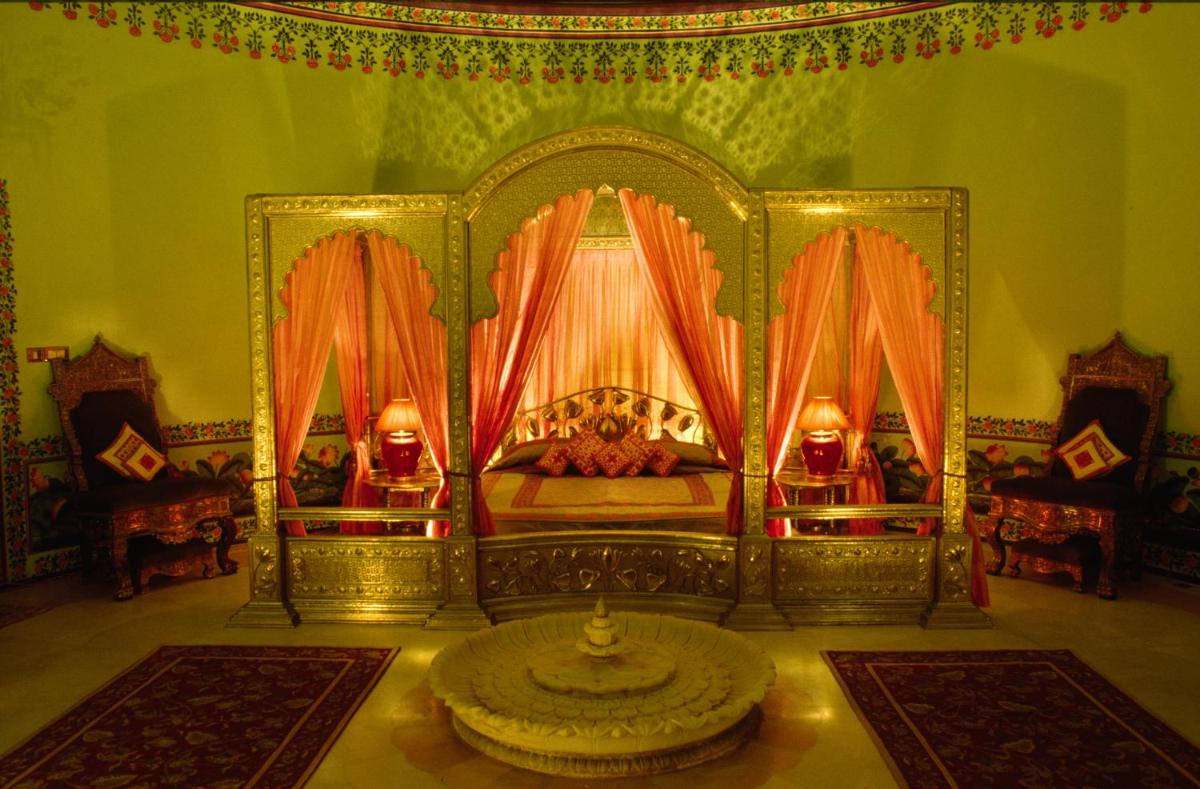 a bedroom with a bed with orange curtains and rugs at Shiv Niwas Palace by HRH Group of Hotels in Udaipur