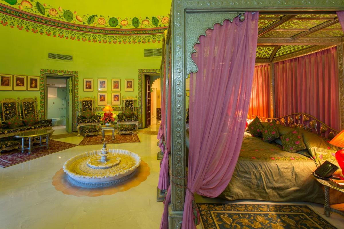a bedroom with a canopy bed and a living room at Shiv Niwas Palace by HRH Group of Hotels in Udaipur