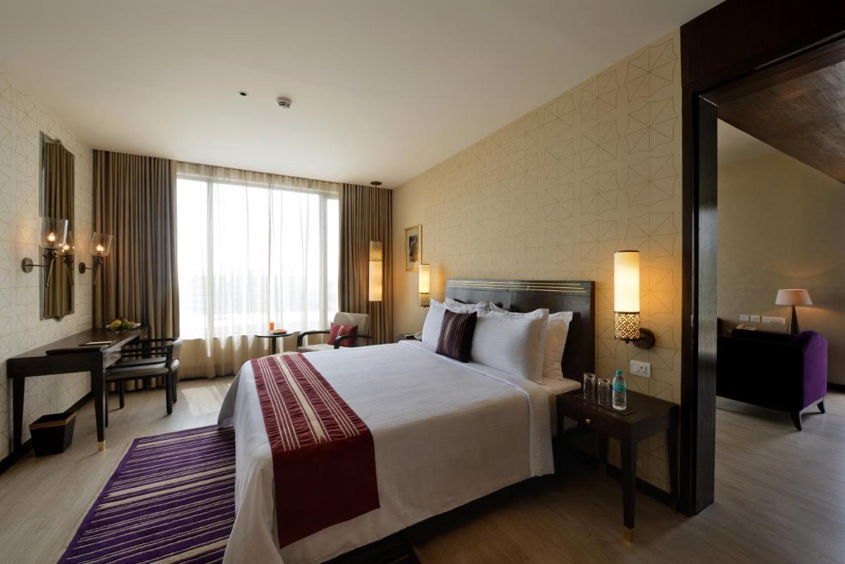 a hotel room with a large bed and a desk at Marasa Sarovar Premiere in Tirupati
