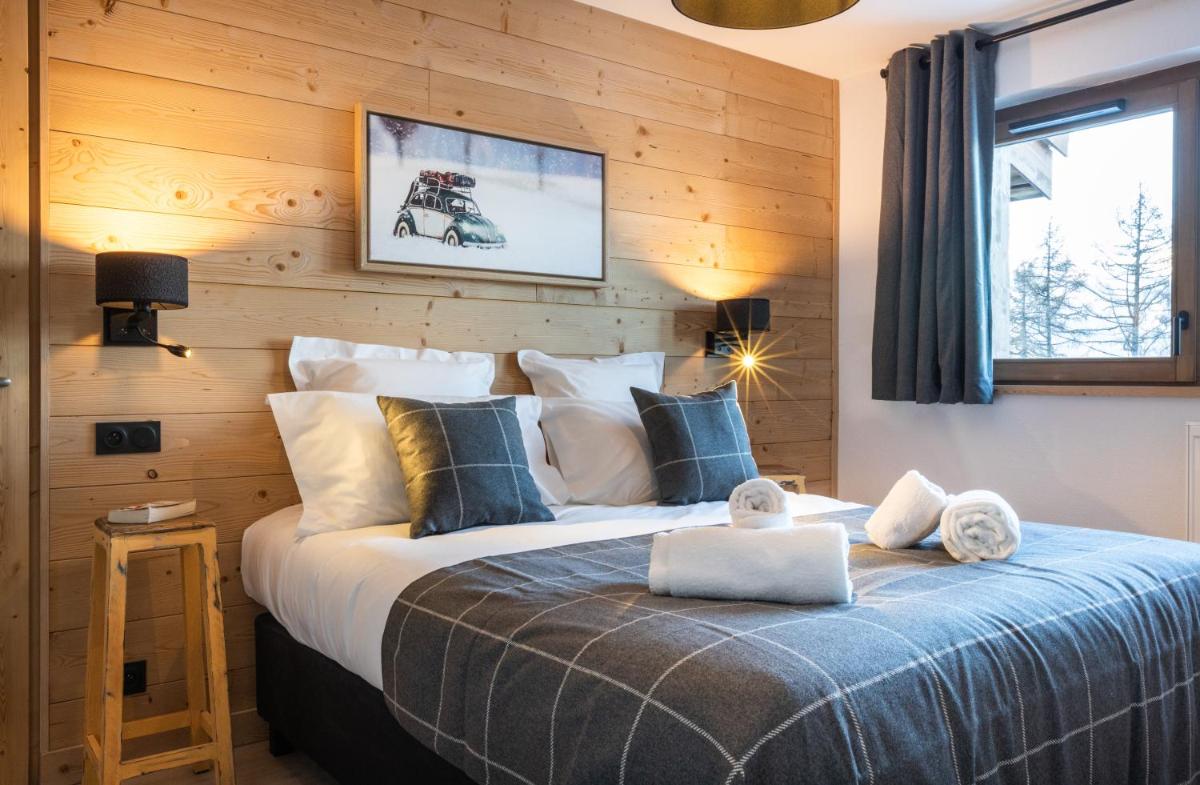 une chambre avec un grand lit avec un mur en bois dans l'établissement TERRESENS - Le Snoroc, à Aime La Plagne