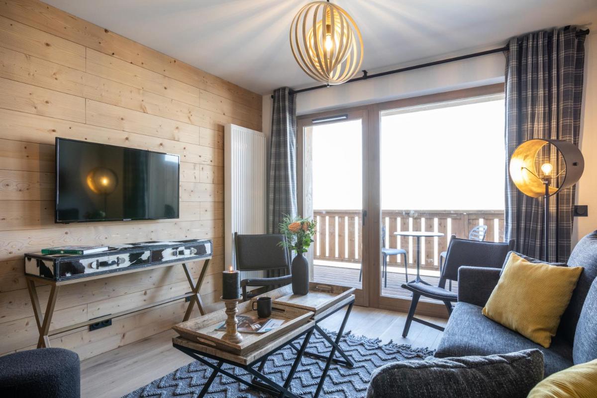 un salon avec un canapé et une télévision dans l'établissement TERRESENS - Le Snoroc, à Aime La Plagne