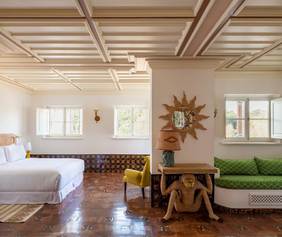 um quarto com uma cama e um sofá verde em Vermelho Melides - Relais & Châteaux em Melides