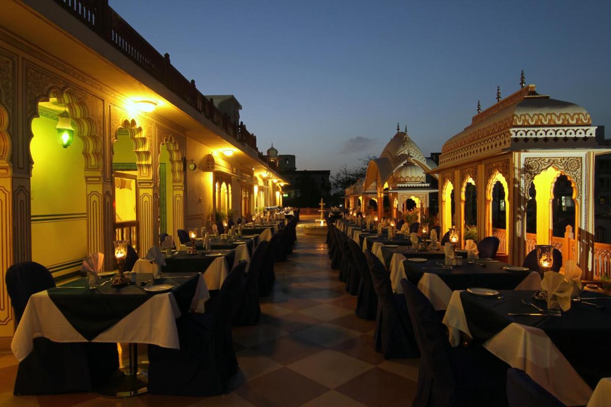 a row of dining tables in a building with lights at Shahpura House in Jaipur