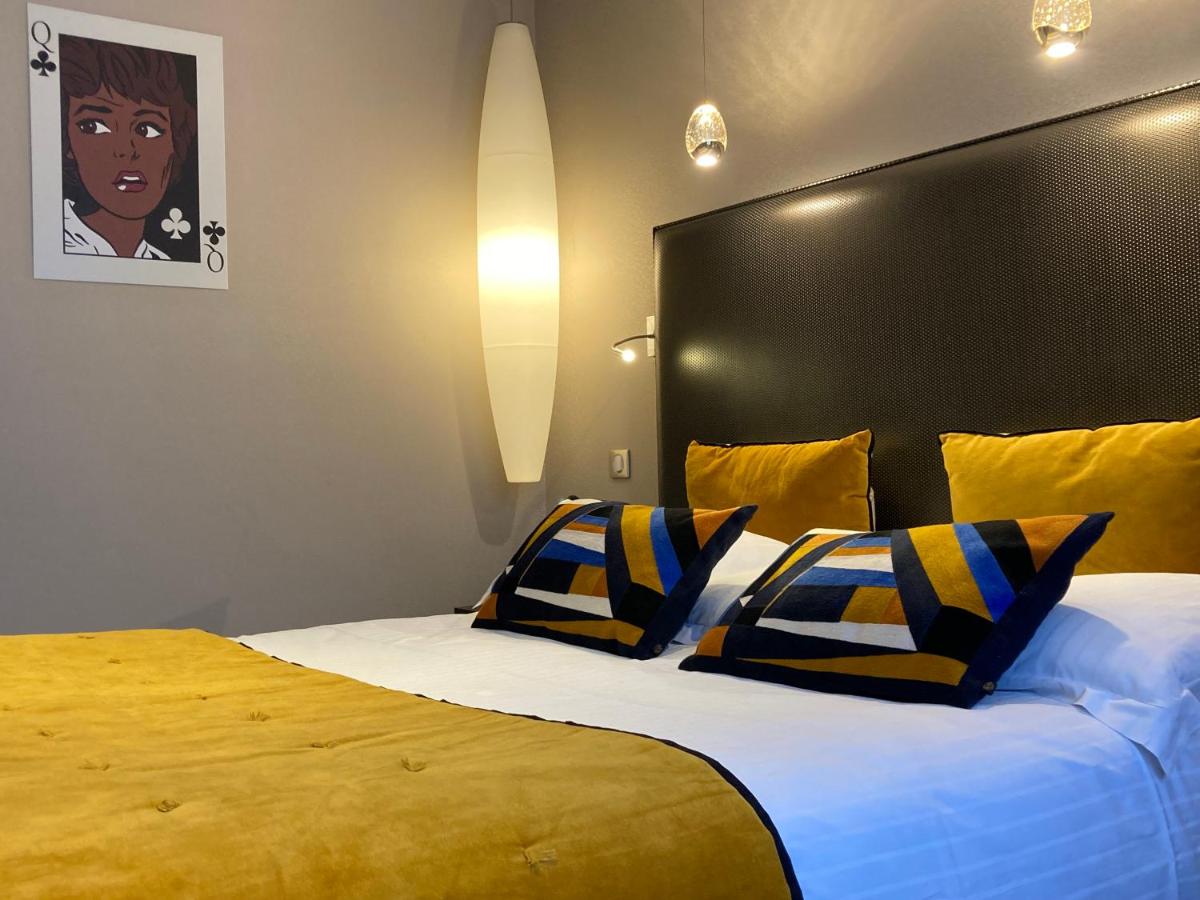 une chambre avec un grand lit aux oreillers bleus et jaunes dans l'établissement Hôtel des Princes, Chambéry Centre, à Chambéry