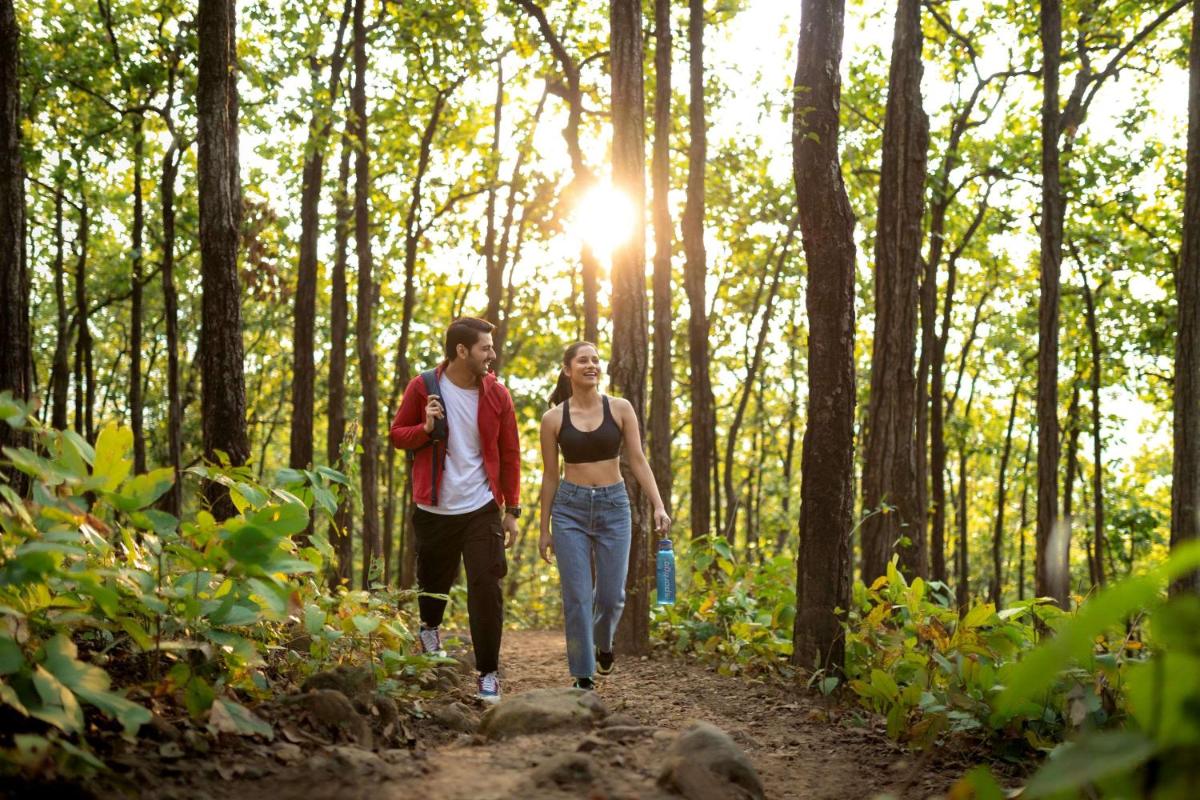 a man and woman walking down a trail in the woods at Hyatt Regency Dehradun Resort and Spa in Dehradun
