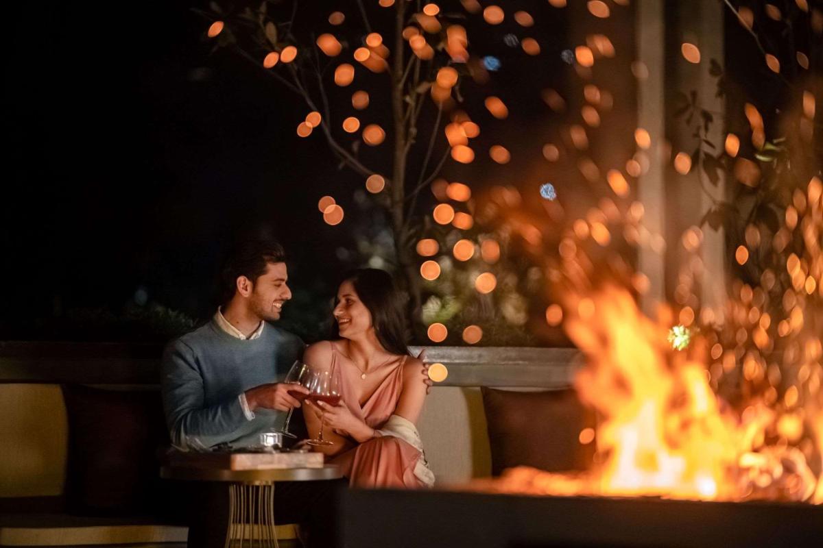 a man and a woman sitting in front of a fire at Hyatt Regency Dehradun Resort and Spa in Dehradun