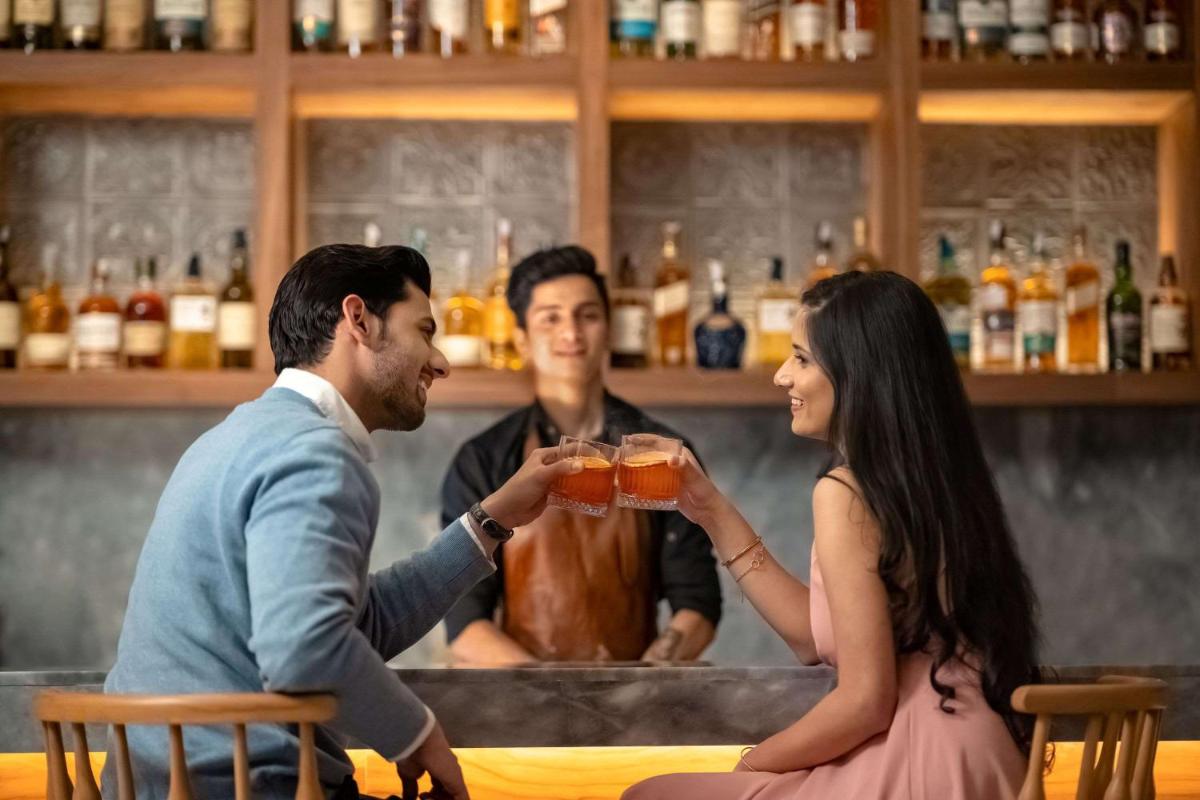 a man and a woman sitting at a bar holding a drink at Hyatt Regency Dehradun Resort and Spa in Dehradun