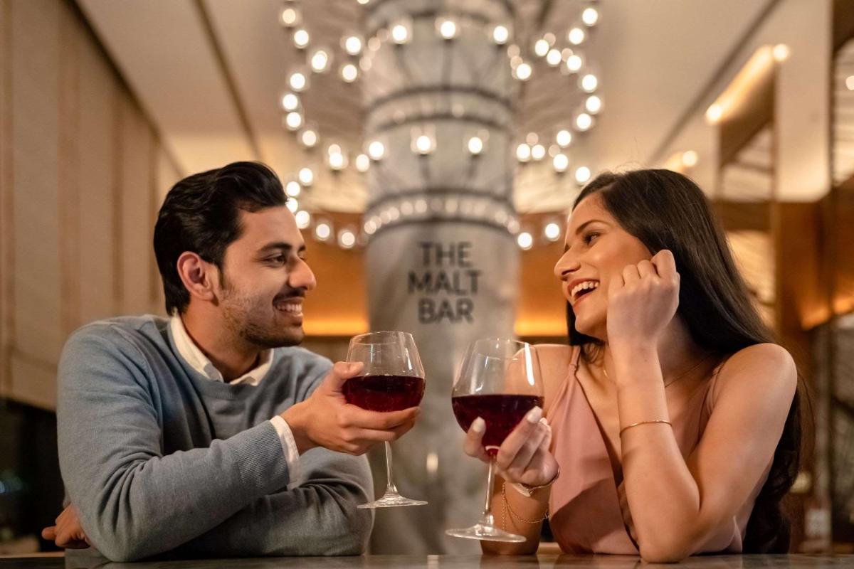 a man and a woman sitting at a table with wine glasses at Hyatt Regency Dehradun Resort and Spa in Dehradun