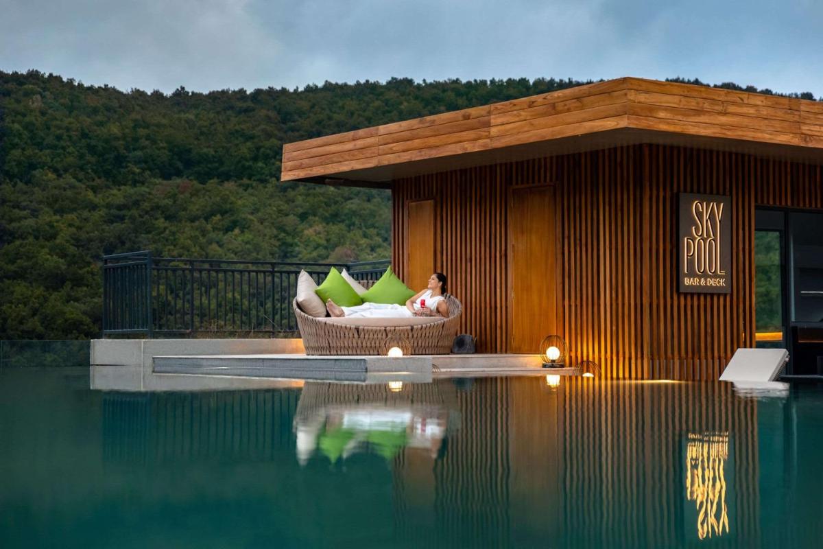 a man sitting in a chair next to a swimming pool at Hyatt Regency Dehradun Resort and Spa in Dehradun
