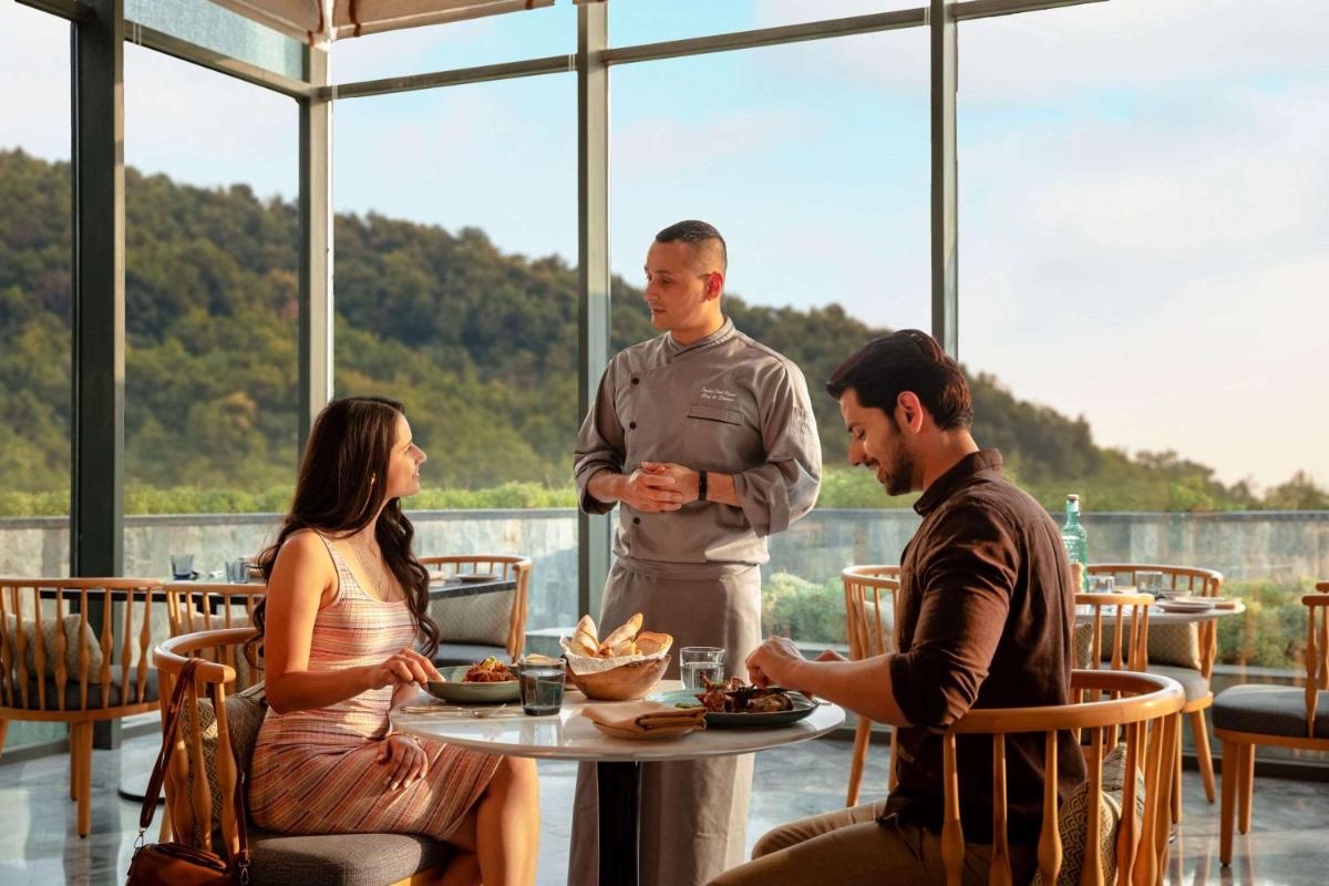 a group of people sitting around a table in a restaurant at Hyatt Regency Dehradun Resort and Spa in Dehradun
