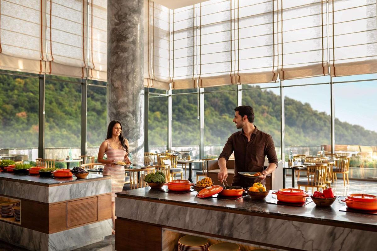 a man and a woman preparing food in a restaurant at Hyatt Regency Dehradun Resort and Spa in Dehradun