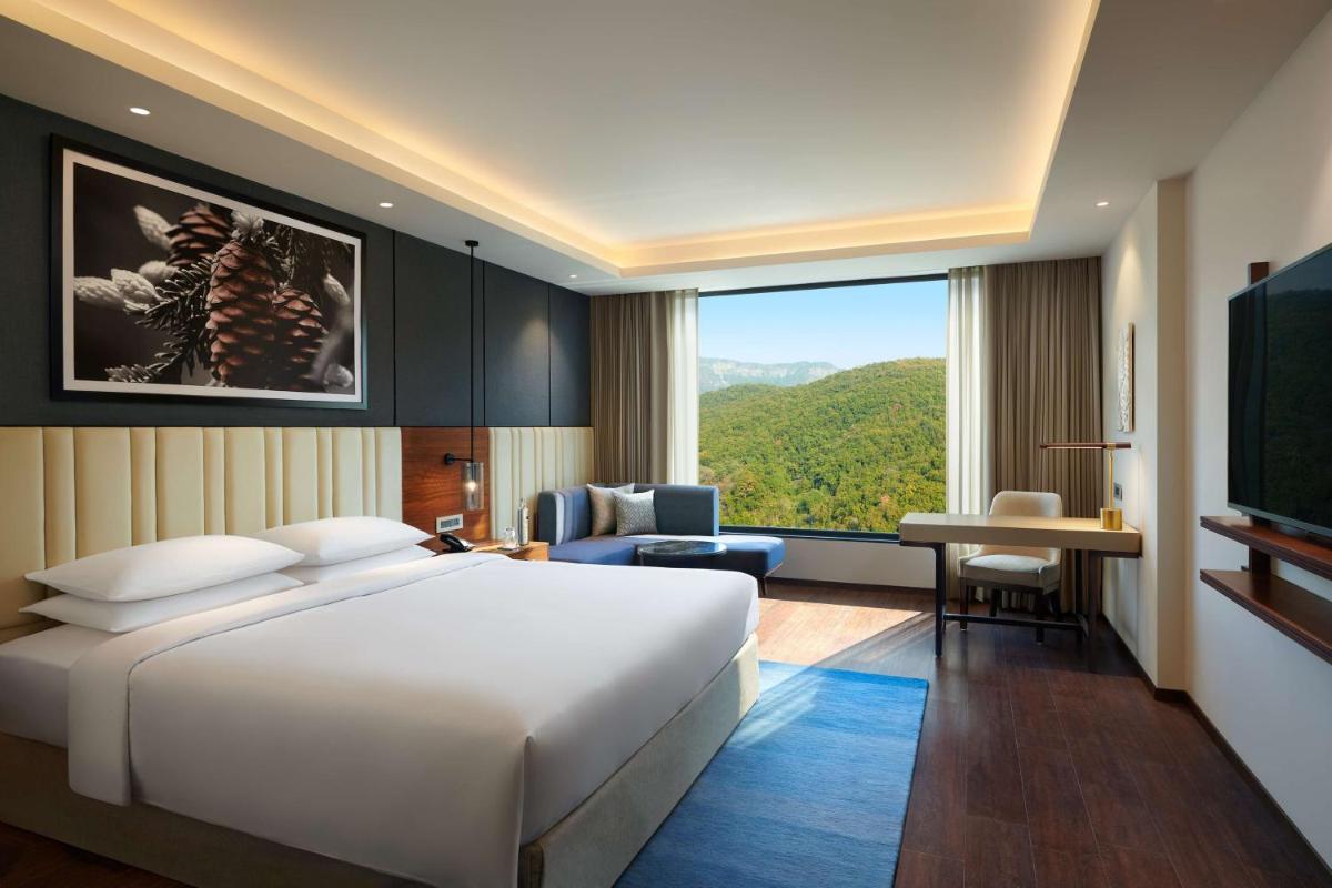 a hotel room with a bed and a large window at Hyatt Regency Dehradun Resort and Spa in Dehradun