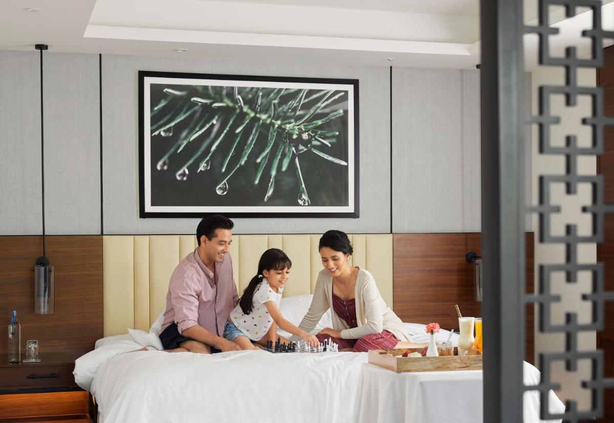 a family sitting on top of a bed at Hyatt Regency Dehradun Resort and Spa in Dehradun