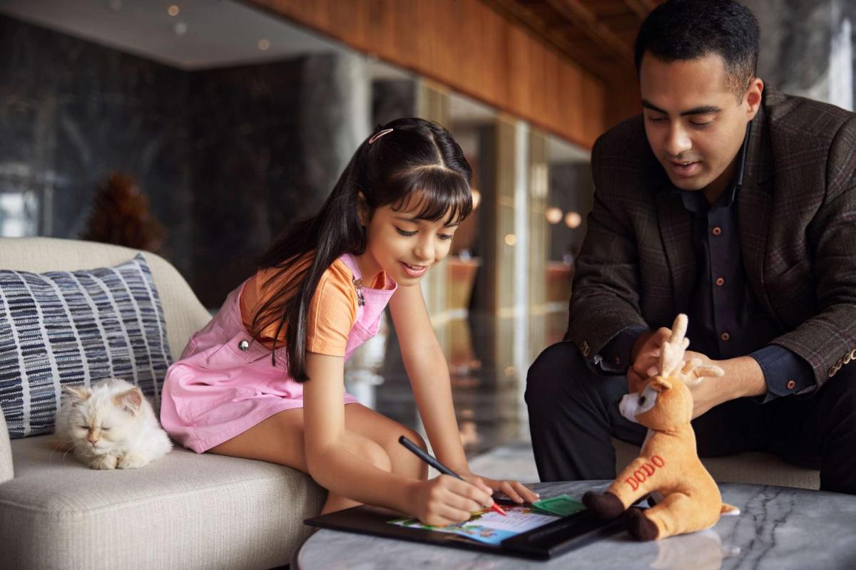 a man and a little girl sitting on a couch with a laptop at Hyatt Regency Dehradun Resort and Spa in Dehradun
