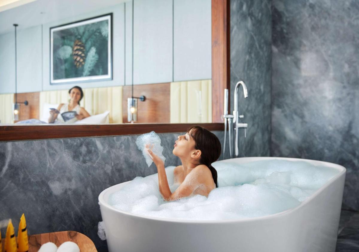 a woman sitting in a bath tub blowing bubbles at Hyatt Regency Dehradun Resort and Spa in Dehradun