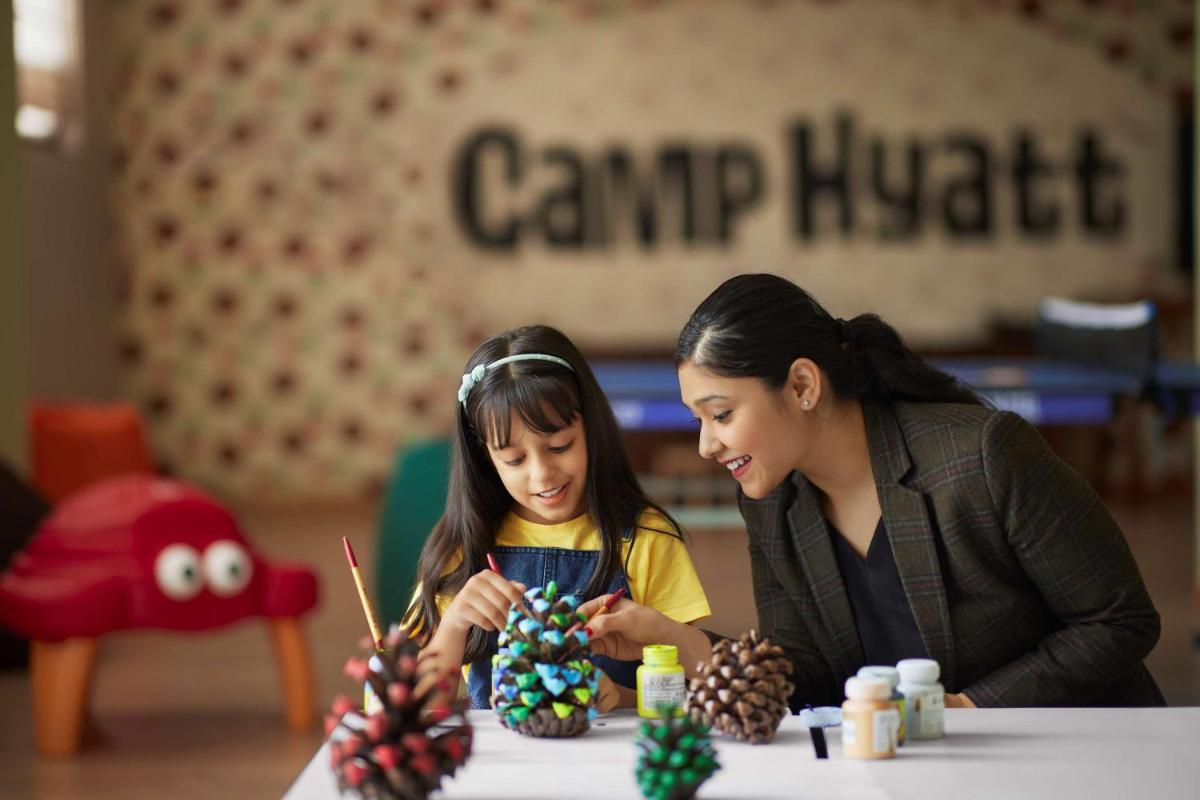a woman and a girl working on pinecones at a table at Hyatt Regency Dehradun Resort and Spa in Dehradun