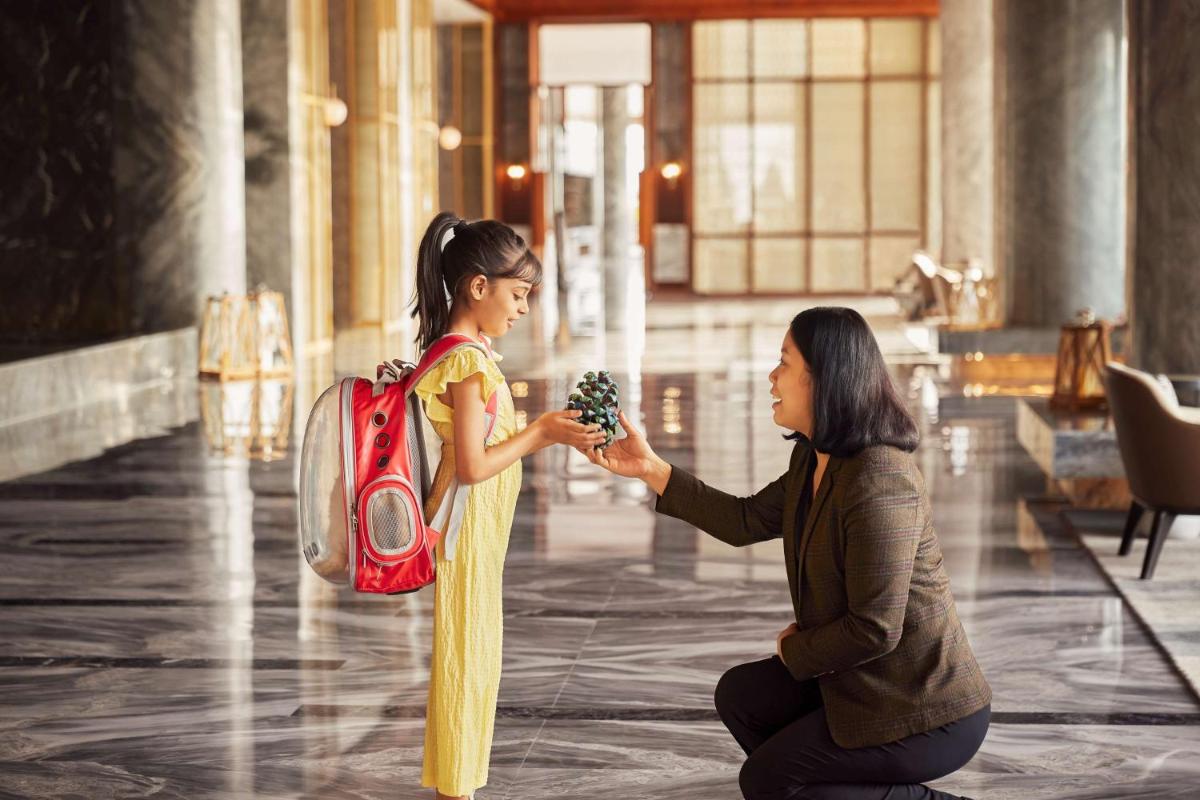 a woman is handing a girl a bunch of flowers at Hyatt Regency Dehradun Resort and Spa in Dehradun