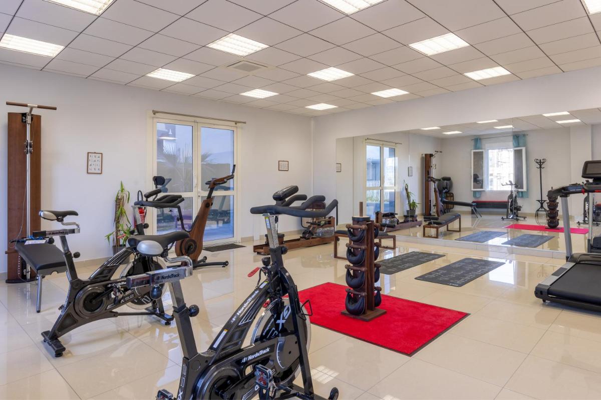 une salle de sport avec plusieurs tapis de course et vélos d'exercice dans l'établissement Best Western Hotel & SPA Pau Lescar Aeroport, à Lescar