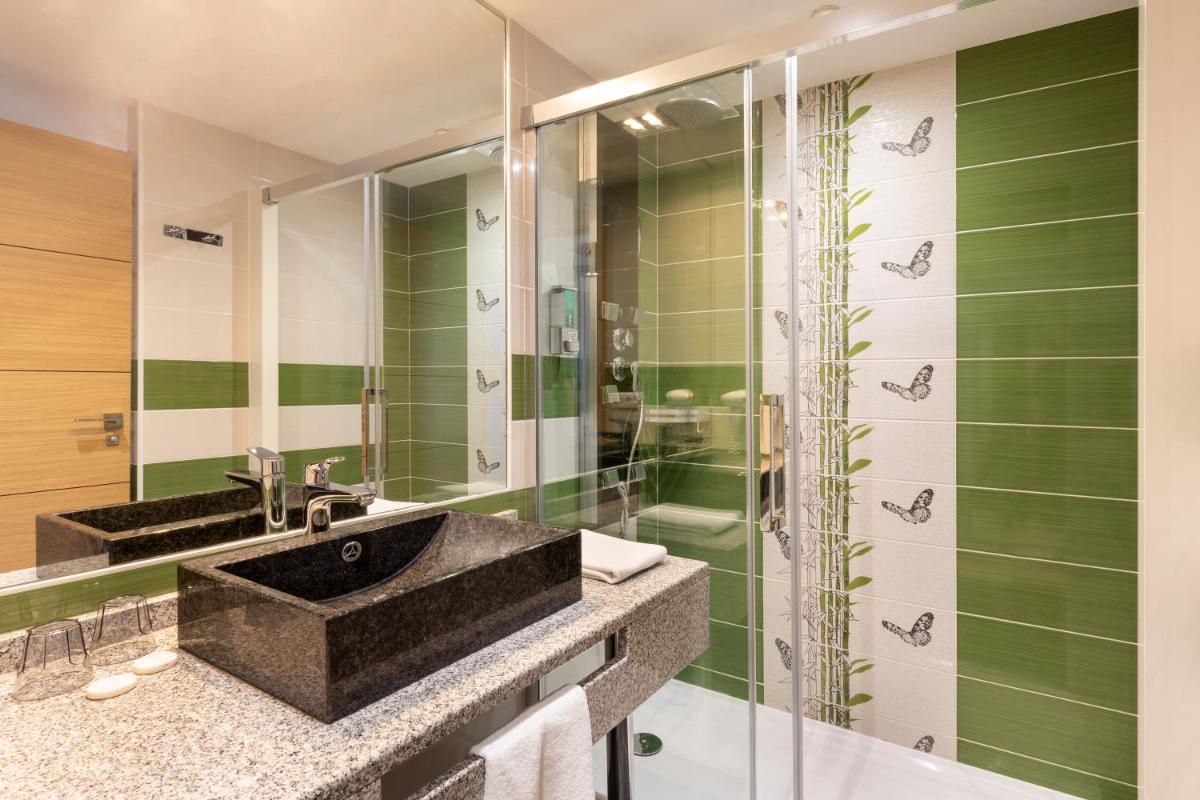 une salle de bains avec deux lavabos et une douche en verre dans l'établissement Best Western Hotel & SPA Pau Lescar Aeroport, à Lescar
