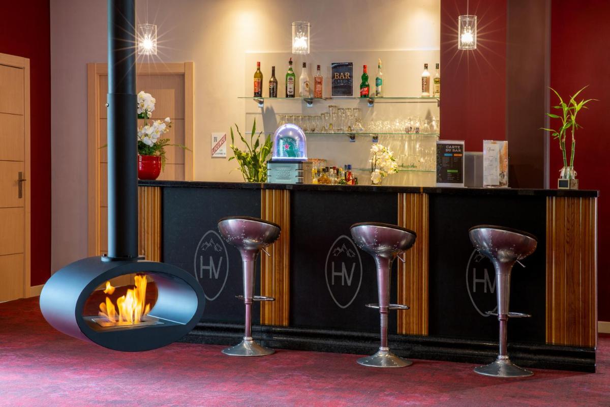 une cheminée devant un bar avec des tabourets dans l'établissement Best Western Hotel & SPA Pau Lescar Aeroport, à Lescar
