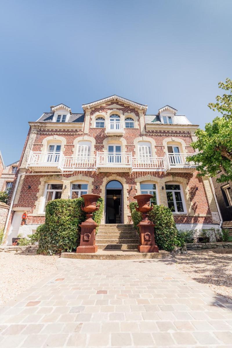 Un grand bâtiment en briques avec un escalier se trouve devant. dans l'établissement La villa 10 HÔTEL SPA, à Étretat