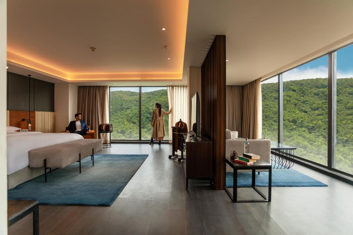 a bedroom with a bed and a woman standing in a room at Hyatt Regency Dehradun Resort and Spa in Dehradun