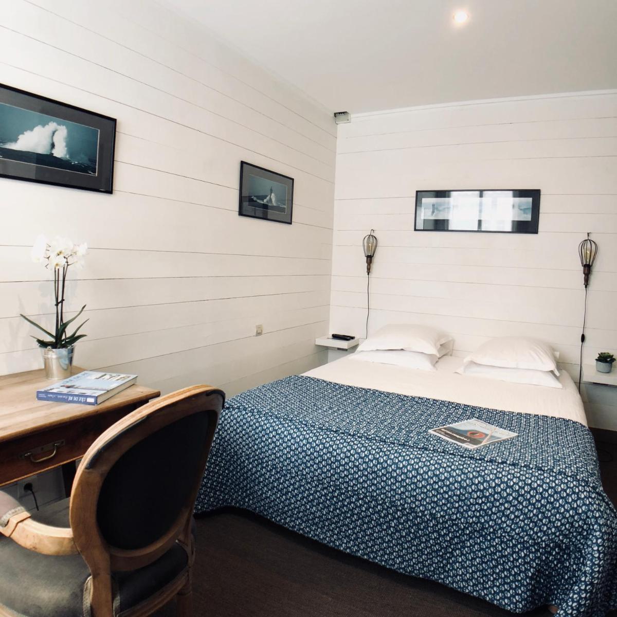 - une chambre avec un lit et un bureau en bois dans l'établissement Hotel L'Océan, au Bois-Plage-en-Ré