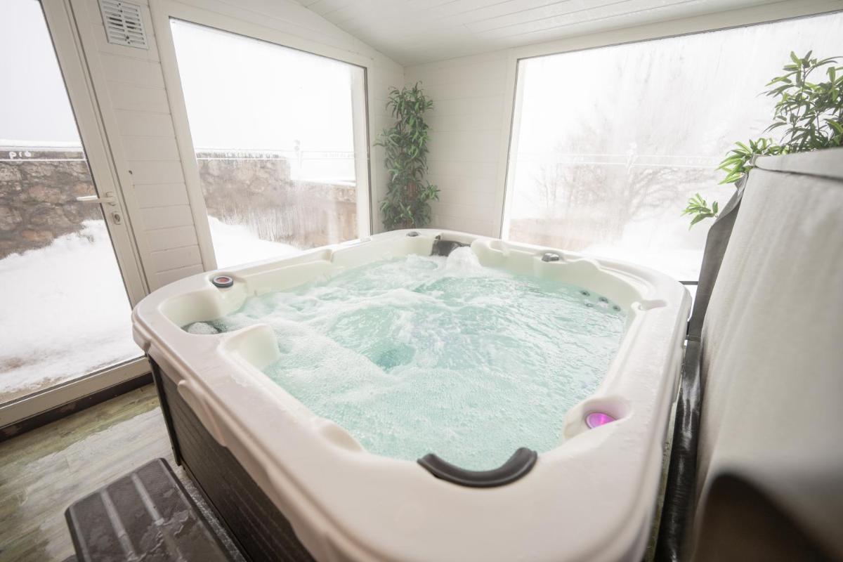 - un bain à remous dans une chambre avec fenêtre dans l'établissement Hob Fort du Pré, à Saint-Bonnet-le-Froid