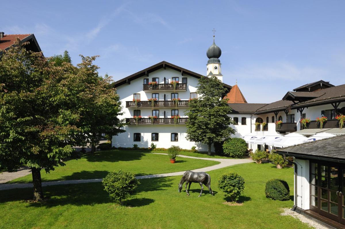 ein Pferd grast im Gras vor einem Gebäude in der Unterkunft Hotel Gut Ising in Chieming