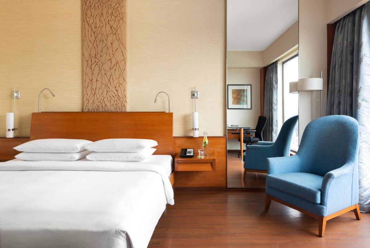 a bedroom with a bed and two blue chairs at Hyatt Pune in Pune