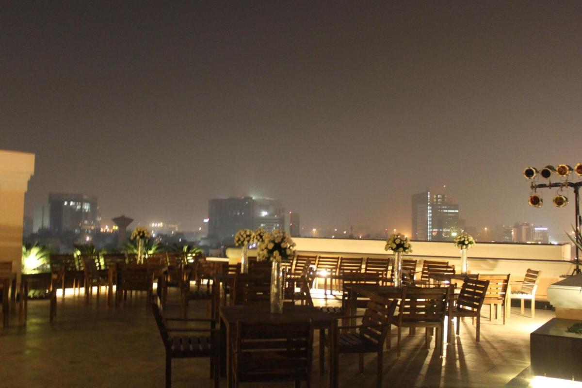a restaurant with tables and chairs on a rooftop at night at The Pllazio Hotel in Gurgaon